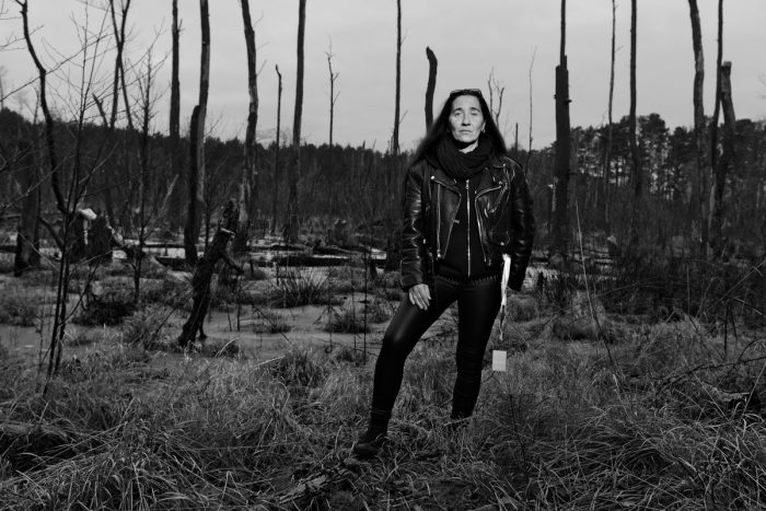 eine Frau steht in an einem morastigem Waldesrand