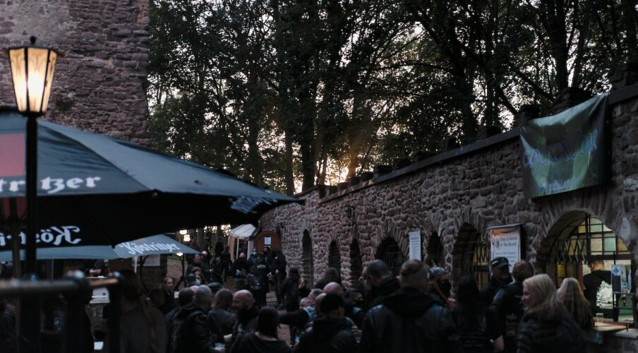Metal Fans versammeln sich zu einem Festival auf einer Burgruine vor Bierständen